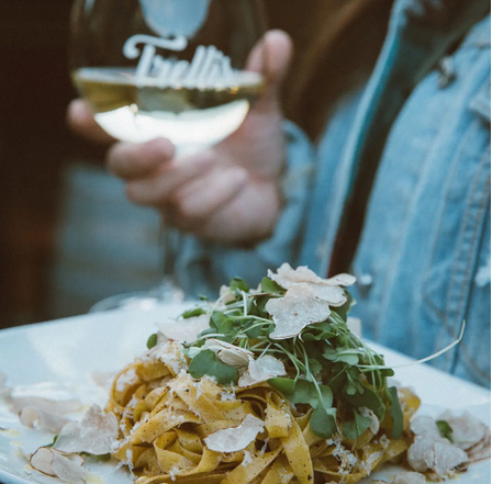 close up a glass of white white and pasta dish with truffle shavings